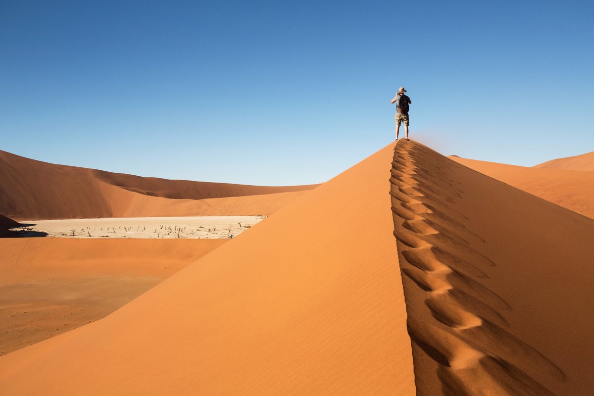 Desert sand dune with a man walking on it