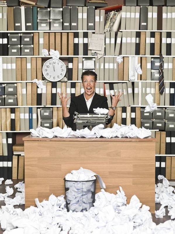 Copywriter surrounded by rejected drafts on paper