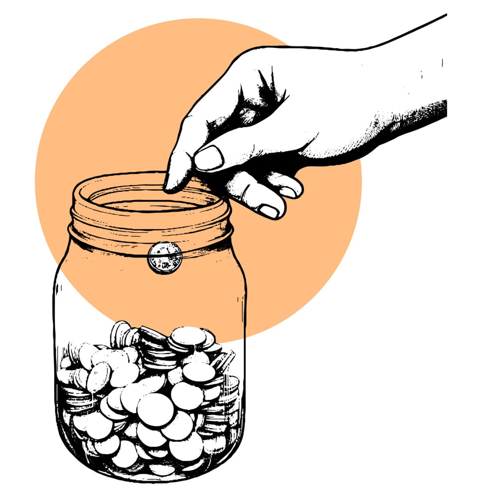 A hand dropping money into a glass jar