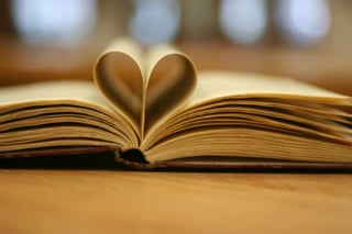 Write with anecdotes and make your message more powerful. Learn to love stories, and learn to write better. Picture shows the pages of a book folded into the shape of a cartoon heart.